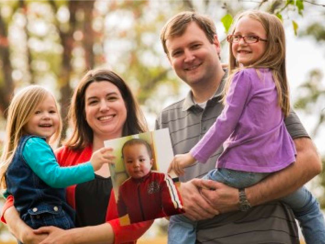 Parents and daughters holding a photo of the child they are adopting