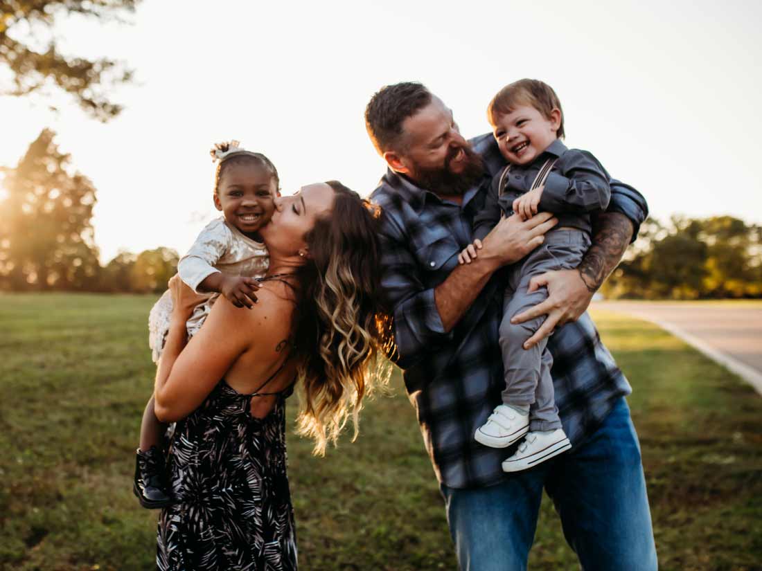 Parents laughing with their two young children at sunset