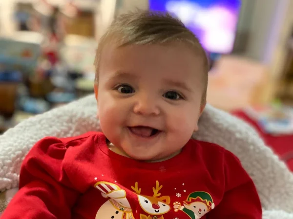 A smiling baby in a red Christmas outfit